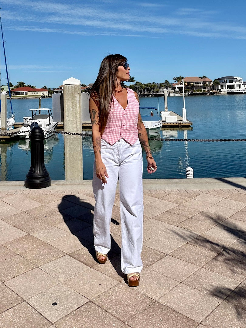 Woman walking by a waterfront with boats and houses in the background
