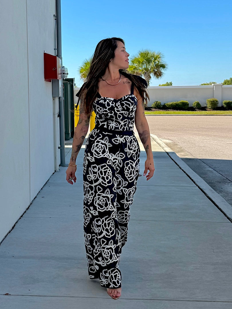 Woman in a black and white patterned dress walking on a sidewalk.