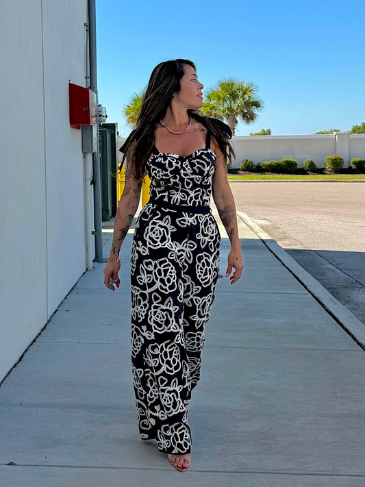 Woman in a black and white patterned dress walking on a sidewalk.