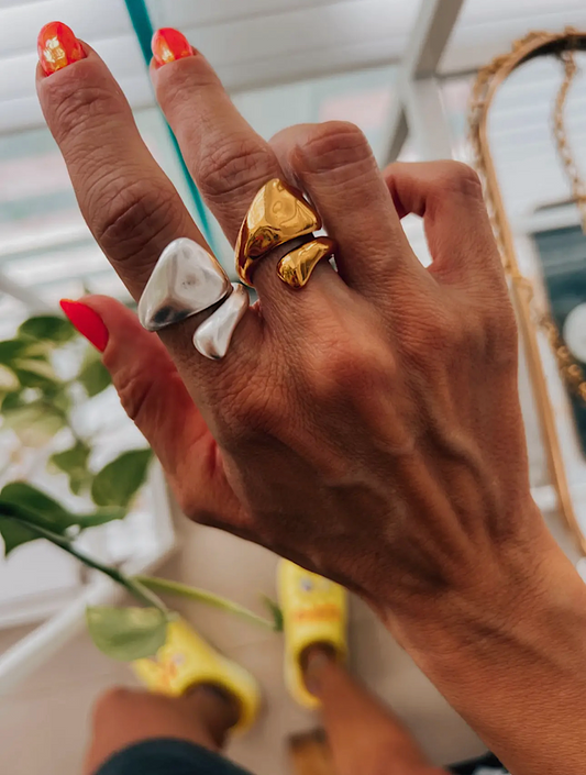 Hand wearing two rings with a blurred indoor background