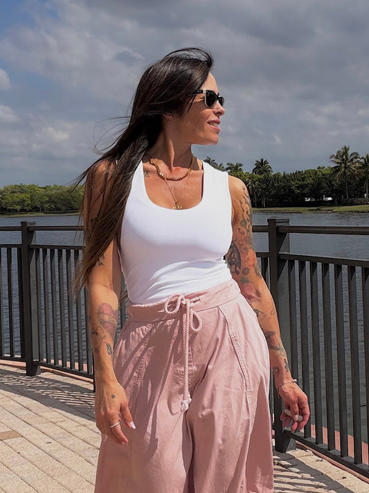 Woman standing on a wooden deck by a waterfront with trees in the background
