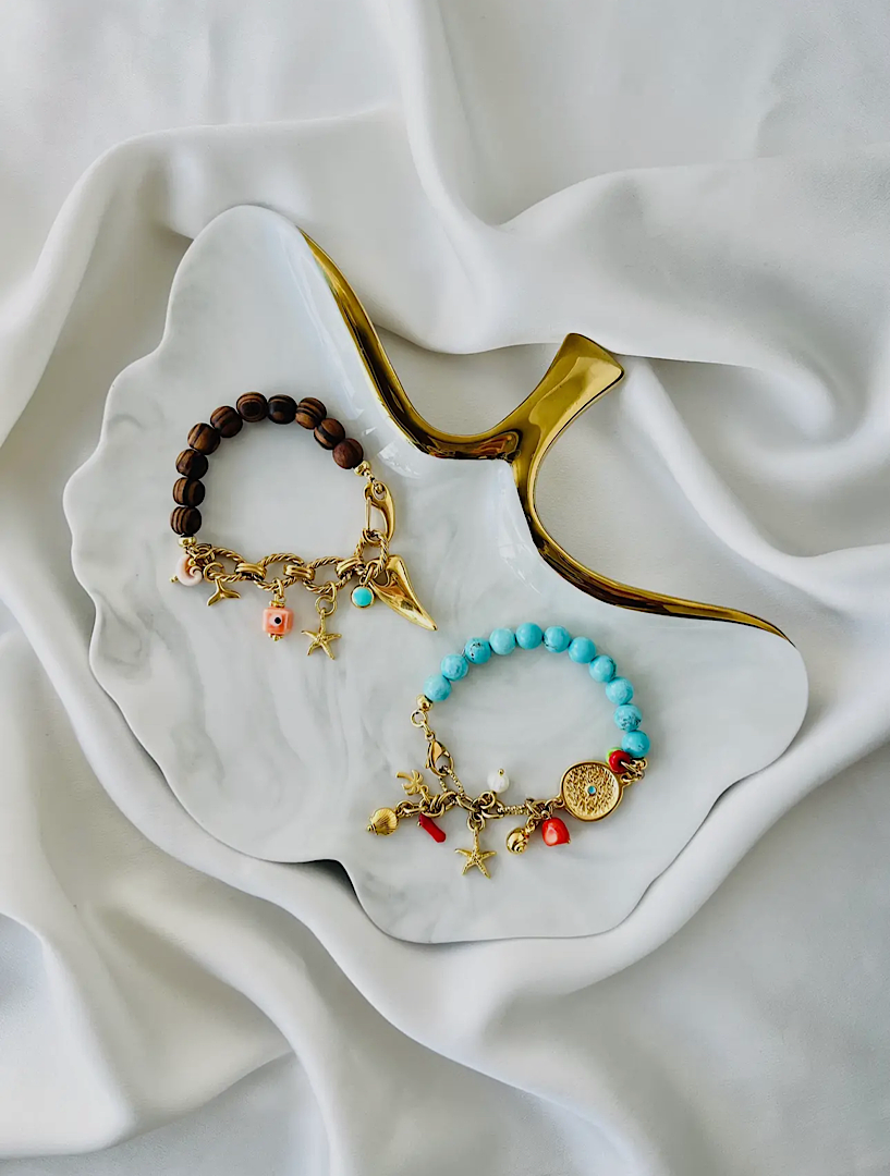 Two bracelets with charms on a white dish
