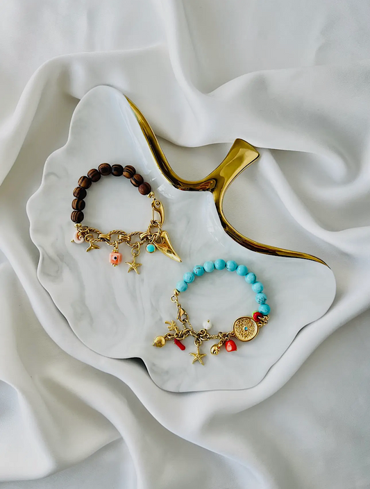 Two bracelets with charms on a white dish