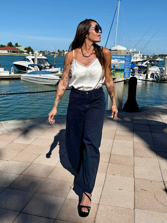 Woman walking by a marina with boats and a clear blue sky.