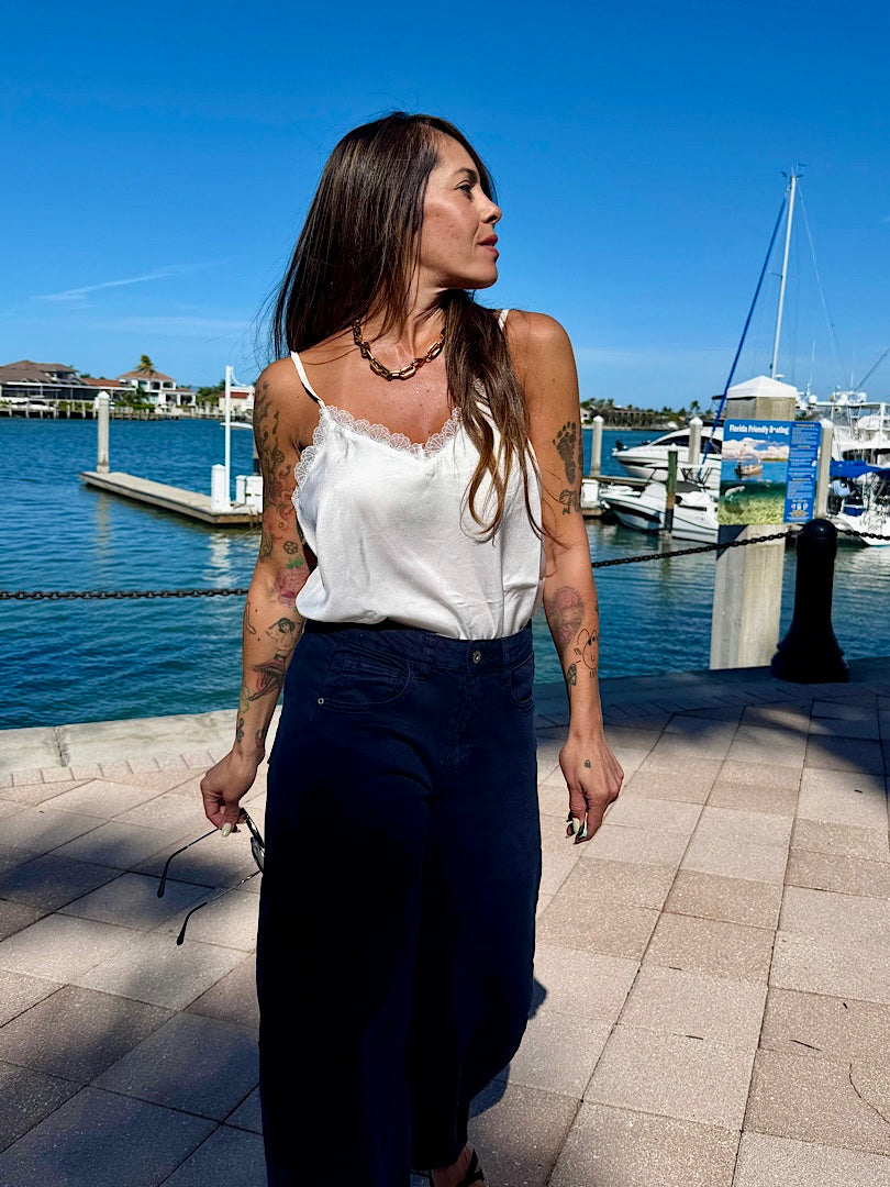 Woman walking by a waterfront with boats and a clear blue sky.