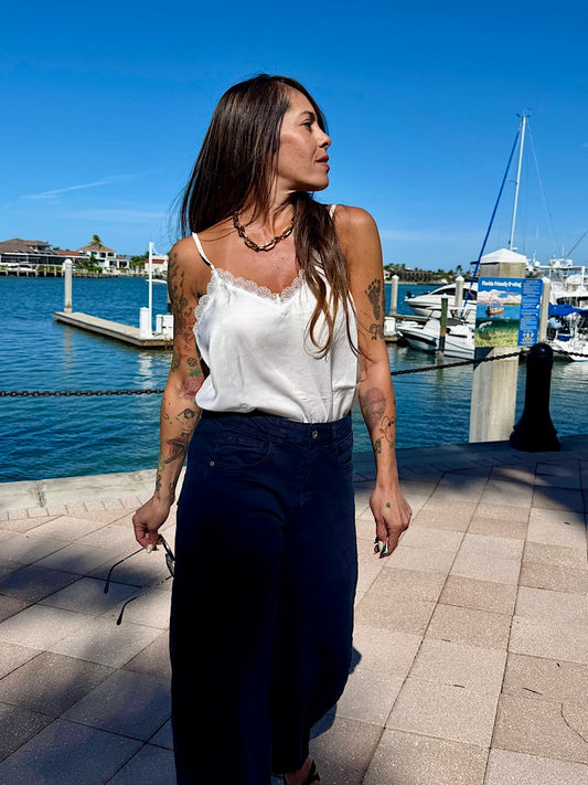 Woman walking by a waterfront with boats and a clear blue sky.