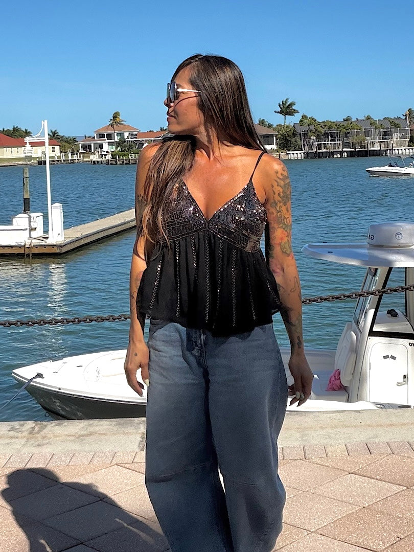 Woman standing by a marina with boats and water in the background