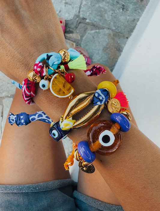 Handmade in Greece with colorful beads and your choice of fruit, glass eye, or gold shell charms. Adjustable with 24K gold-plated accents, perfect alone or stacked.